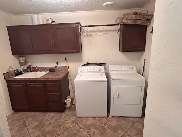 laundry room with cabinets, a textured ceiling, sink, light tile patterned flooring, and washing machine and dryer