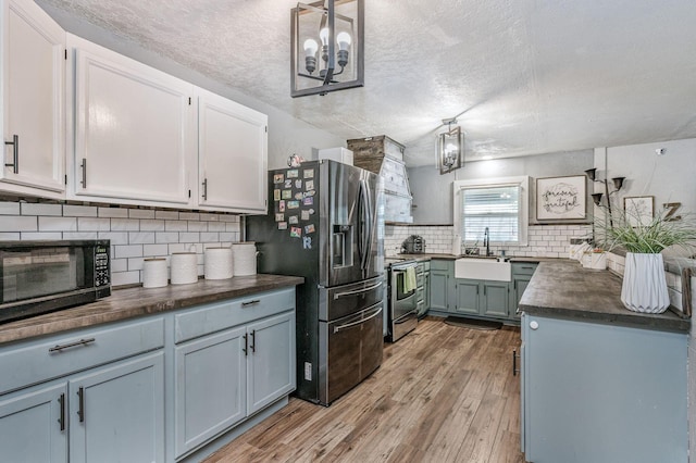 1607 N Mary-Ellen St, Pampa, TX 79065 - kitchen featuring a sink, stainless steel appliances, dark countertops, tasteful backsplash, and light wood-style floors
