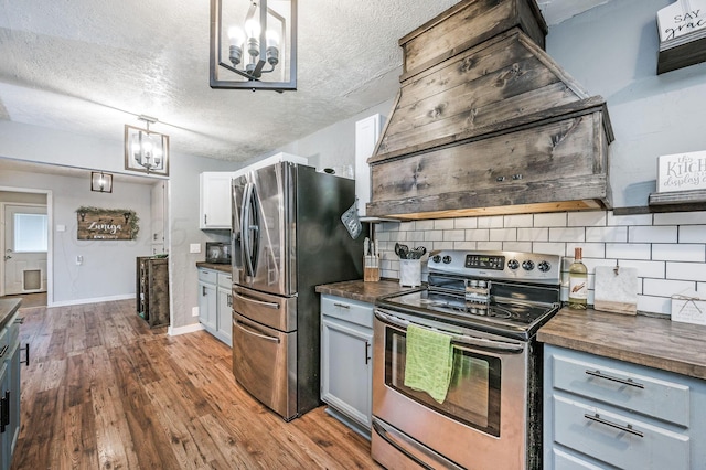 1607 N Mary-Ellen St, Pampa, TX 79065 - kitchen with stainless steel appliances, a chandelier, decorative backsplash, a textured ceiling, and range hood