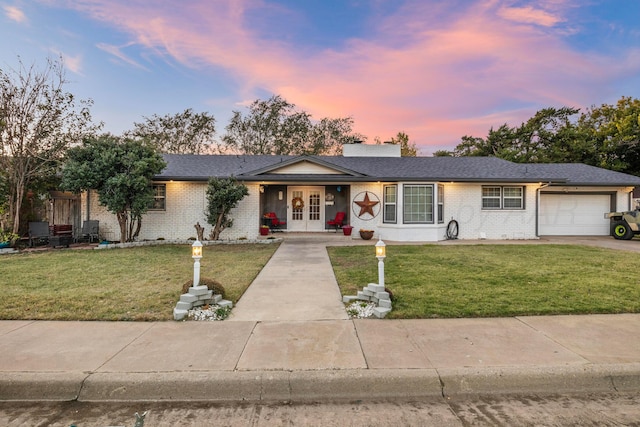 single story home featuring a garage, a lawn, and french doors