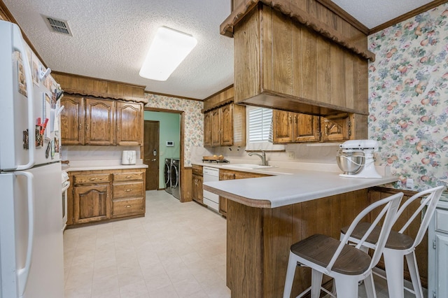 314 Fir St, Hereford, TX 79045 - kitchen with wallpapered walls, a peninsula, brown cabinetry, a sink, and a textured ceiling