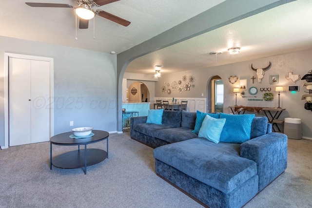 215 Abilene St, Borger, TX 79007 - living area with arched walkways, carpet, ceiling fan, and a textured ceiling