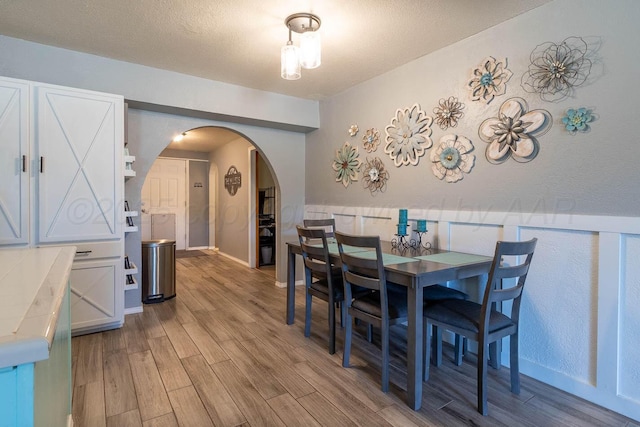 215 Abilene St, Borger, TX 79007 - dining space with arched walkways, light wood-style floors, and a textured ceiling