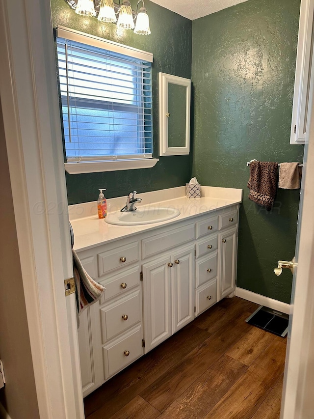 112 Houston St, Borger, TX 79007 - bathroom featuring wood finished floors, a textured wall, vanity, and a chandelier