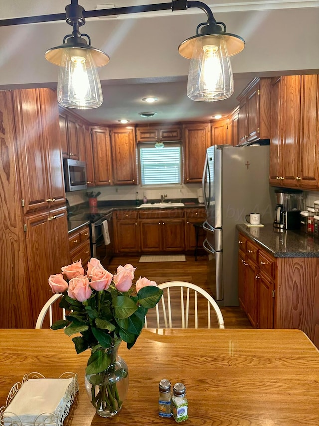 112 Houston St, Borger, TX 79007 - kitchen featuring stainless steel appliances, a sink, brown cabinetry, and decorative light fixtures