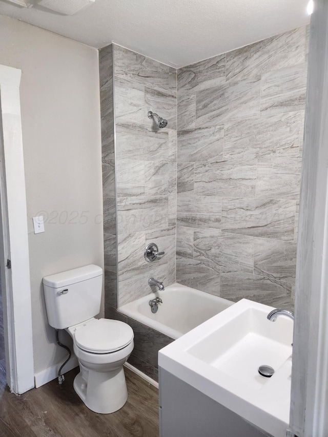 full bath with toilet, wood finished floors, washtub / shower combination, and a sink