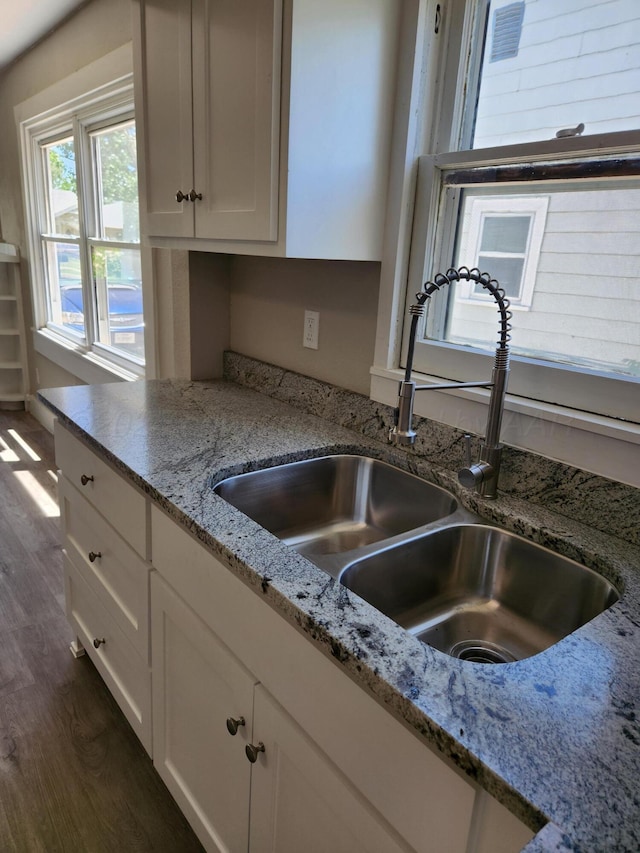 kitchen featuring a sink, dark wood-type flooring, white cabinets, and light stone counters