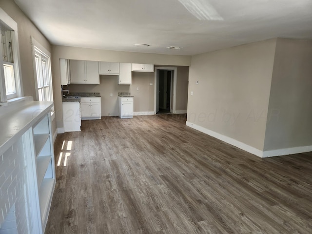 kitchen with dark wood-style floors, white cabinets, and baseboards
