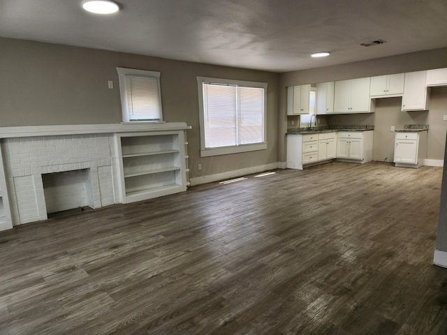 904 S Mississippi St, Amarillo, TX 79106 - unfurnished living room featuring baseboards, dark wood-type flooring, a brick fireplace, and a sink