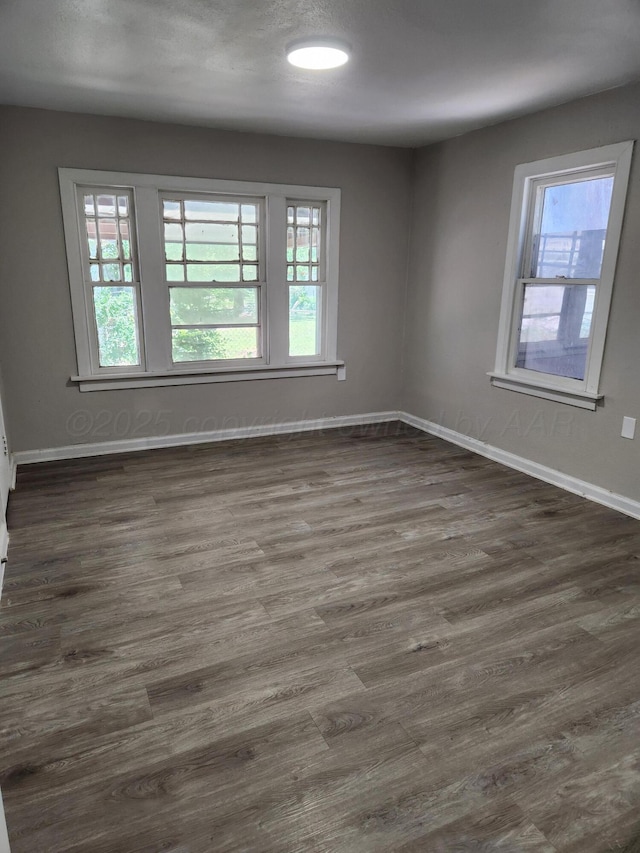 spare room with plenty of natural light, dark wood-style flooring, and baseboards
