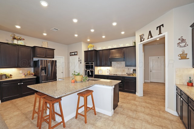 9709 Sydney Dr, Amarillo, TX 79119 - kitchen featuring stainless steel appliances, tasteful backsplash, light stone countertops, recessed lighting, and a breakfast bar area