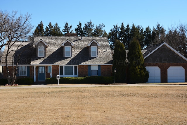 cape cod home featuring brick siding and a front yard