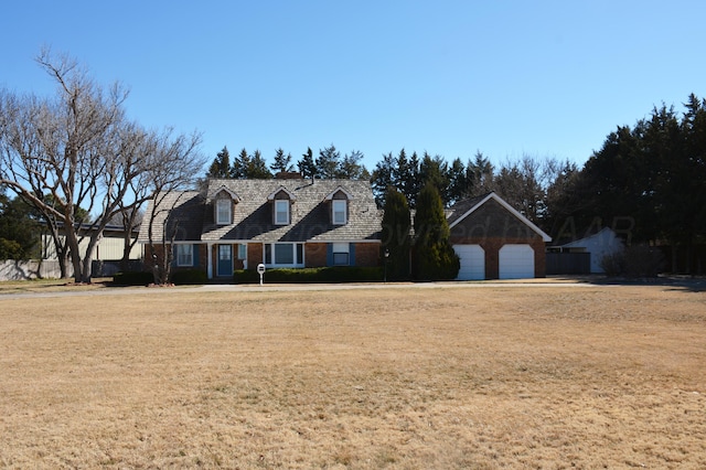 new england style home with a garage and a front lawn