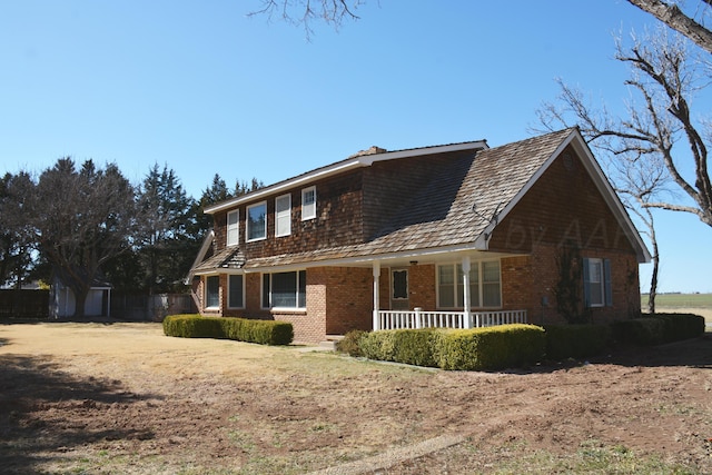 view of front of property with covered porch, a storage shed, brick siding, and an outdoor structure