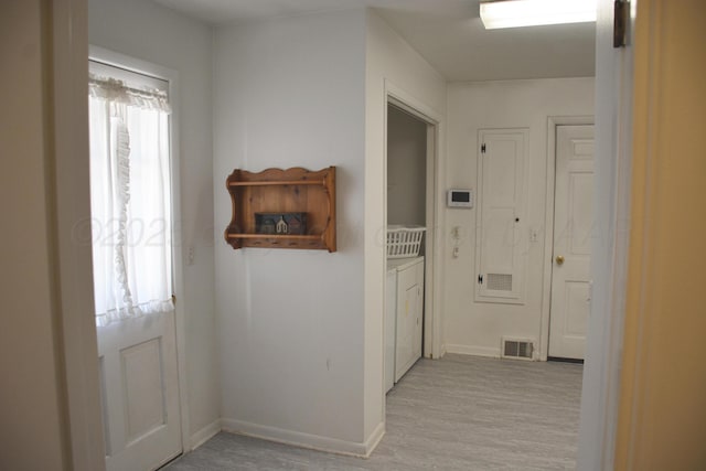 hall featuring plenty of natural light, visible vents, light wood-style flooring, and baseboards