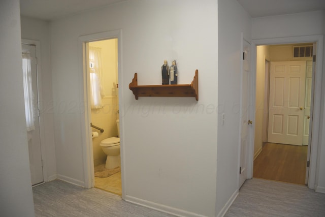 hallway featuring baseboards, visible vents, and wood finished floors