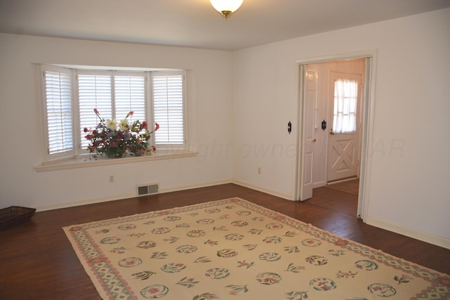 spare room with baseboards, visible vents, dark wood finished floors, and a wealth of natural light