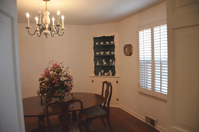 dining room featuring a wealth of natural light, dark wood-style flooring, visible vents, and a notable chandelier