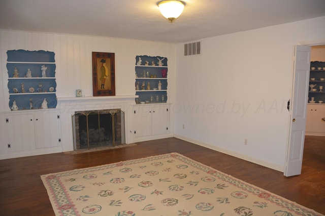 living area featuring visible vents, baseboards, built in features, dark wood-style floors, and a fireplace with flush hearth