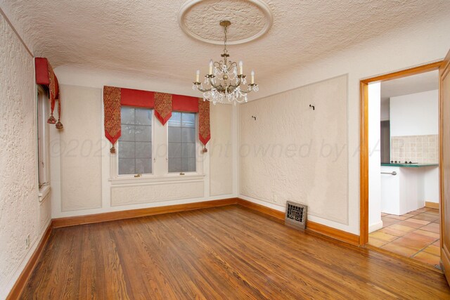 2615 S Hayden St, Amarillo, TX 79109 - unfurnished room with a chandelier, wood finished floors, a textured ceiling, and a textured wall