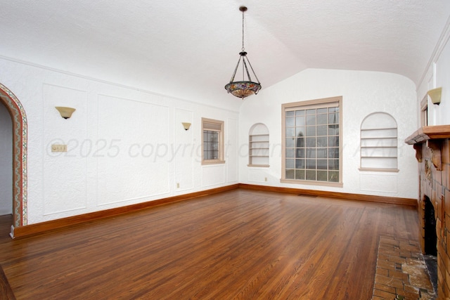 2615 S Hayden St, Amarillo, TX 79109 - unfurnished living room featuring built in features, vaulted ceiling, dark wood-type flooring, arched walkways, and a textured ceiling