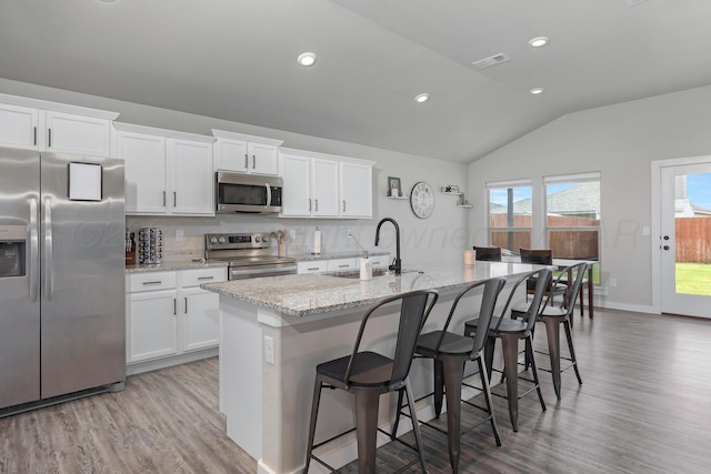1801 Callaway Pl, Amarillo, TX 79118 - kitchen featuring appliances with stainless steel finishes, lofted ceiling, light wood-style floors, white cabinetry, and a center island with sink