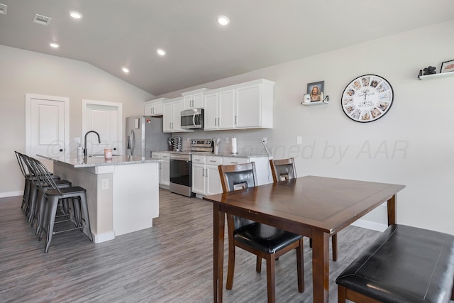 1801 Callaway Pl, Amarillo, TX 79118 - kitchen featuring stainless steel appliances, white cabinetry, a breakfast bar area, an island with sink, and wood finished floors