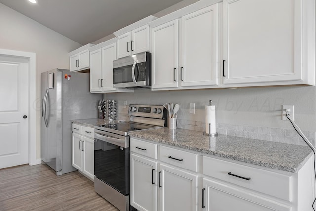 1801 Callaway Pl, Amarillo, TX 79118 - kitchen with appliances with stainless steel finishes, vaulted ceiling, white cabinets, light stone counters, and light wood-style flooring