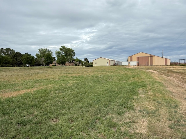 14680 County Road 6, Booker, TX 79005 - view of green lawn featuring a pole building, a garage, an outbuilding, and driveway