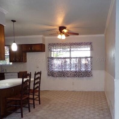 kitchen featuring ornamental molding, a kitchen bar, ceiling fan, hanging light fixtures, and dishwasher