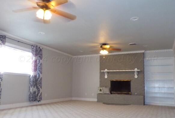 unfurnished living room featuring a brick fireplace, ceiling fan, ornamental molding, and carpet