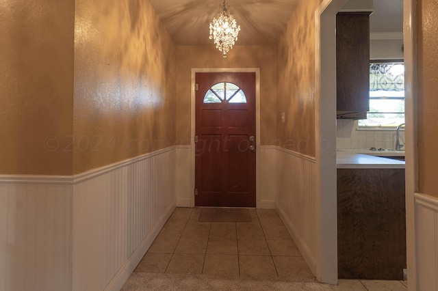 doorway with a chandelier and light tile patterned floors