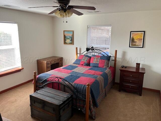 carpeted bedroom featuring ceiling fan and a textured ceiling