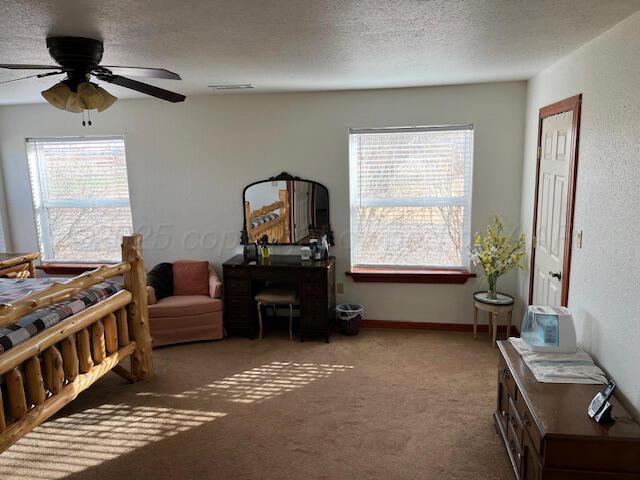 carpeted bedroom featuring multiple windows, ceiling fan, and a textured ceiling