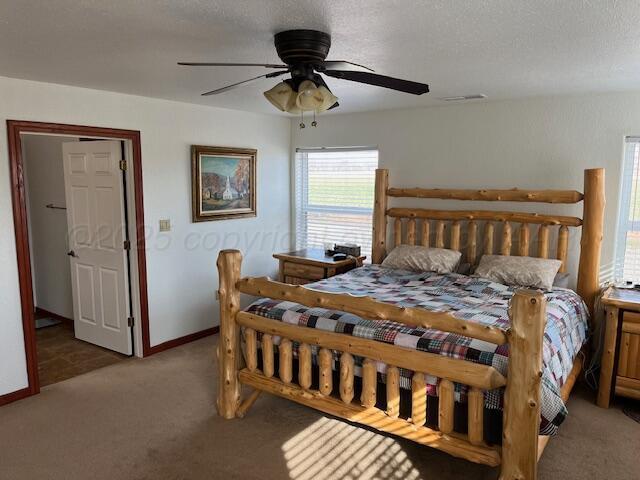 bedroom with ceiling fan, carpet flooring, and a textured ceiling