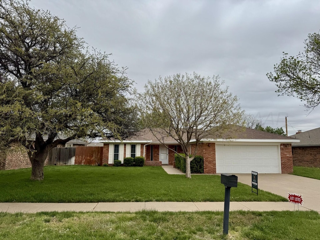 ranch-style house featuring concrete driveway, an attached garage, brick siding, and a front yard