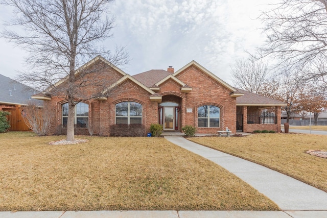 ranch-style home with brick siding, roof with shingles, a chimney, fence, and a front lawn