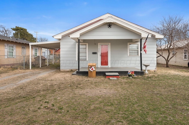 view of front facade with dirt driveway, a porch, a front yard, fence, and an attached carport