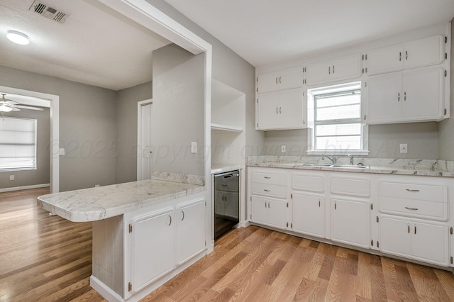 kitchen featuring a peninsula, visible vents, white cabinets, black dishwasher, and light wood-type flooring