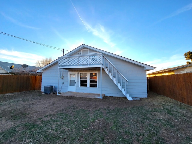 rear view of property featuring a patio, central air condition unit, a lawn, a fenced backyard, and stairs