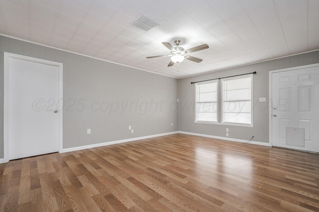 empty room with light wood-type flooring, visible vents, and crown molding