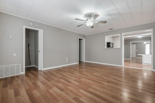 empty room with baseboards, light wood-style flooring, visible vents, and a ceiling fan