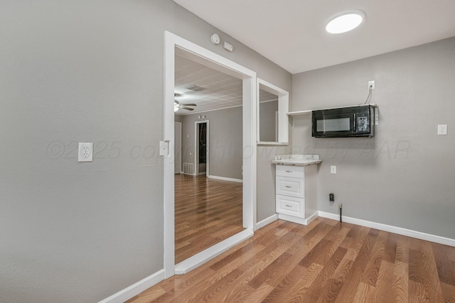 kitchen with a ceiling fan, black microwave, baseboards, and light wood finished floors