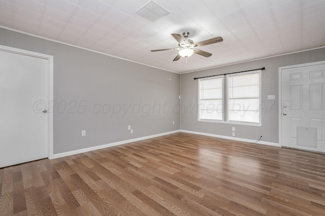 unfurnished room with visible vents, ornamental molding, ceiling fan, light wood-type flooring, and baseboards