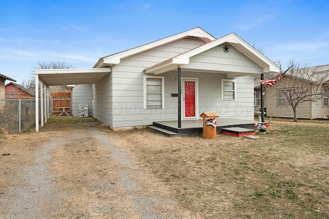 view of front of house with a carport, driveway, a porch, and fence