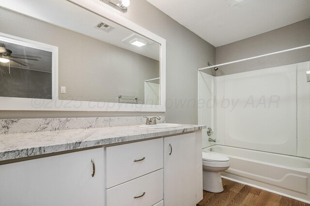 bathroom featuring visible vents, toilet, wood finished floors, vanity, and shower / bathing tub combination