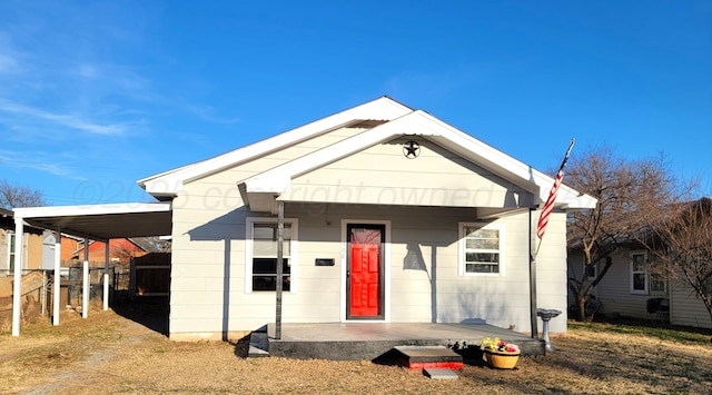 bungalow-style house with covered porch, a carport, and fence