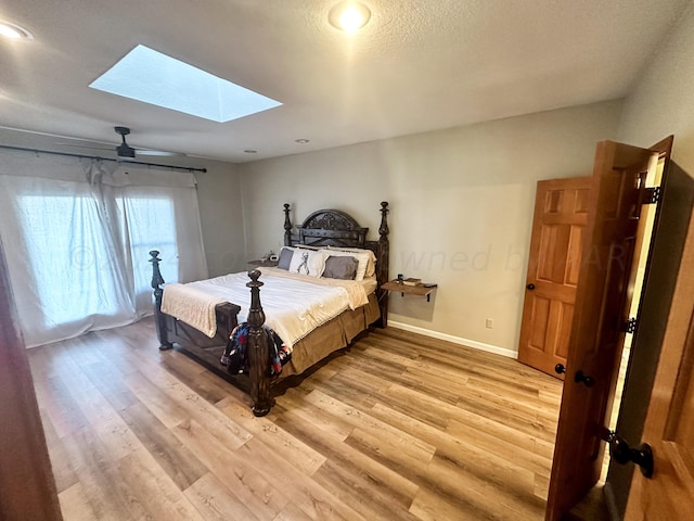 bedroom featuring a skylight, a textured ceiling, hardwood / wood-style flooring, and ceiling fan