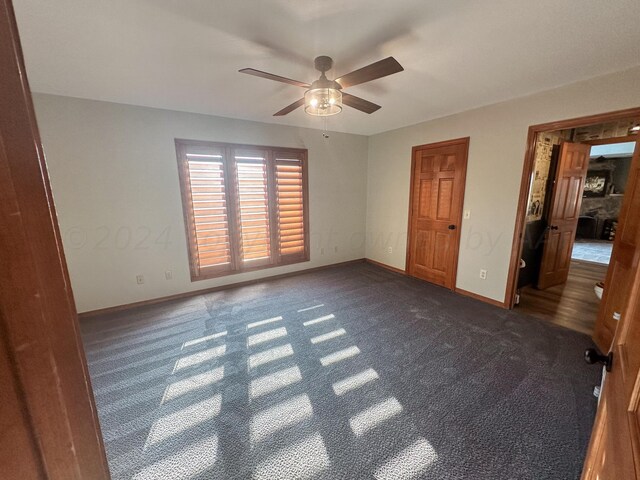 unfurnished bedroom featuring ceiling fan and dark carpet