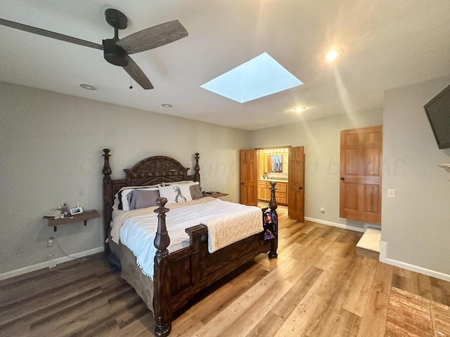 bedroom featuring ceiling fan, light hardwood / wood-style flooring, and a skylight